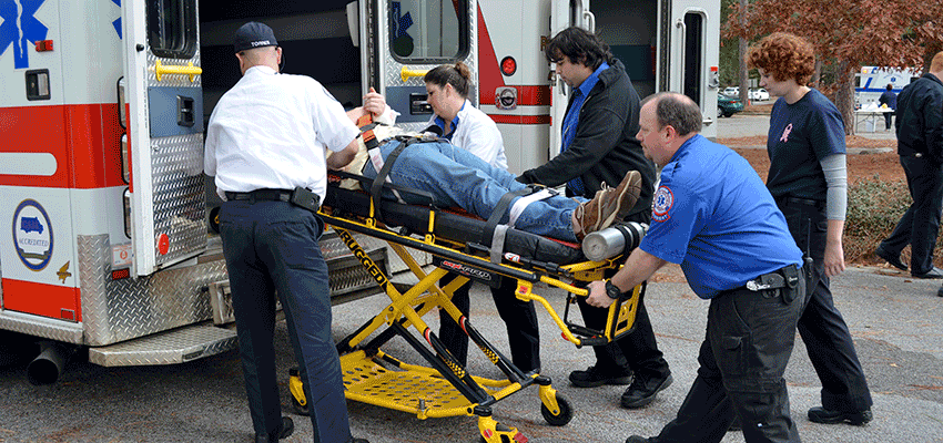 Image of EMS students putting someone in an ambulance.