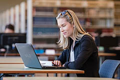 Female working on laptop in library.