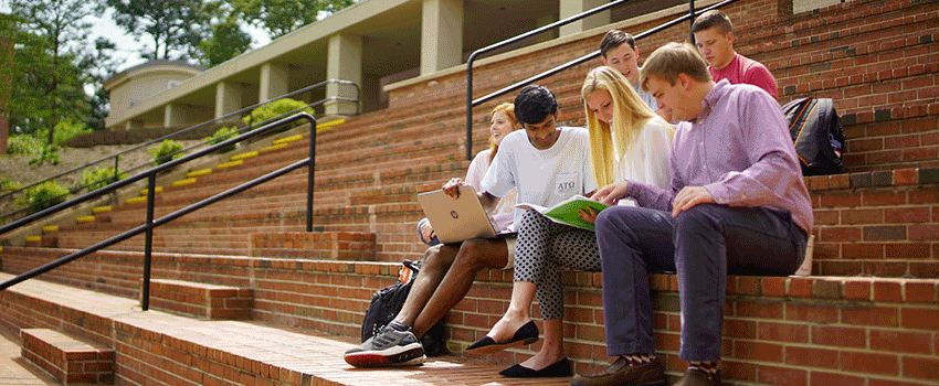 Students studying outside on stairs on campus.