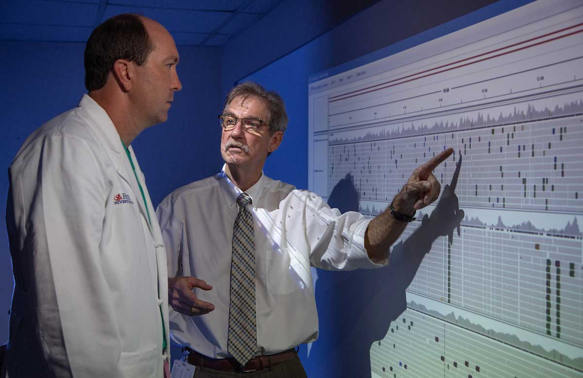 Photo of Dr. Gillespie and fellow PI pointing to bioinformatics on a screen