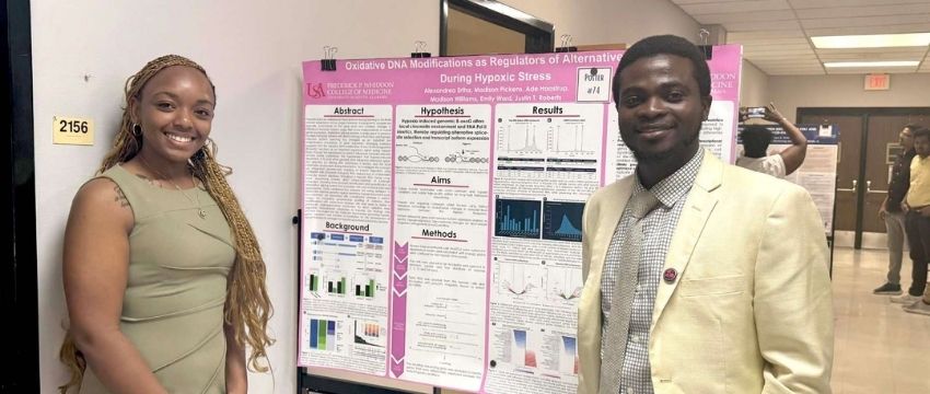Two students standing in front of research poster.