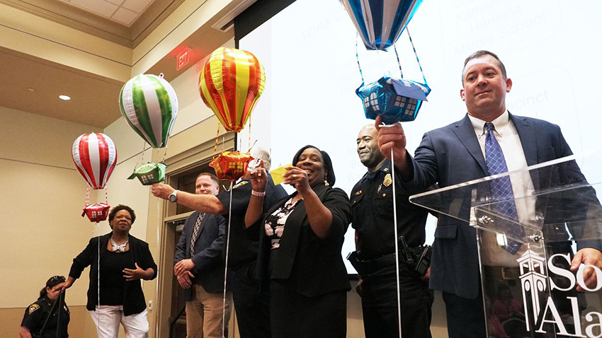 Principals of four Mobile County middle schools, accompanied by captains from partner police precincts, prepare to find out what order their schools will go in as the SOAR program is implemented. From left are Capt. Angela Prine, Booker T. Washington Middle School Principal Johnnie Williams, Katherine H. Hankins Middle School Principal Joshua Verkouille, Capt. Kevin Rogers (reaching for balloon), Palmer Pillans Middle School Principal Tammy George, Capt. Lee Laffitte and Bernice J. Causey Middle School Principal Jason Smith.Mike Kittrell/University of South Alabama