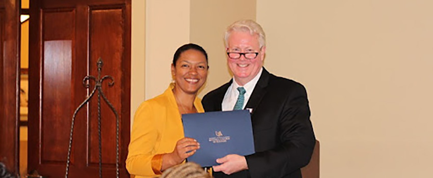 Woman smiling holding award with professor.