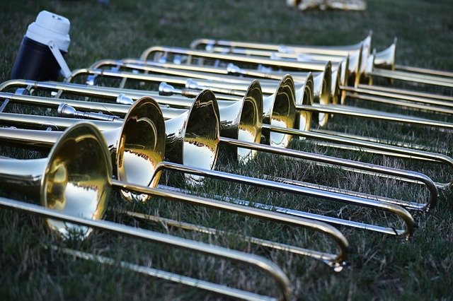 Trombones are pictured laying in a row in the grass.