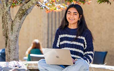 South student working on laptop outside.
