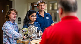 Three students working with professor in lab.