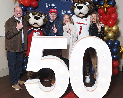 President Bonner and his wife and Vice President Kent and her husband with Southpaw and Ms. Pawla behind 50th anniversary sign.