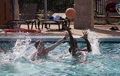 Two male students playing water basketball in Campus Rec outdoor pool.