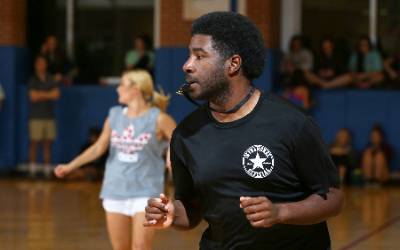 Students playing intramural sport in gym with referee.