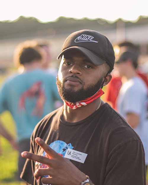 IFC Student holding up the peace sign with fingers outside at an event.