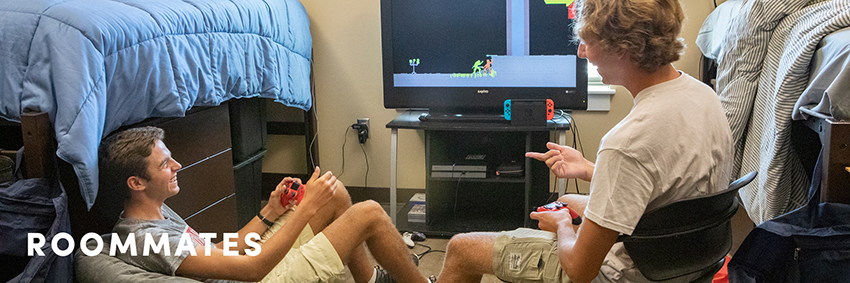 Two male students playing video games in their dorm room.
