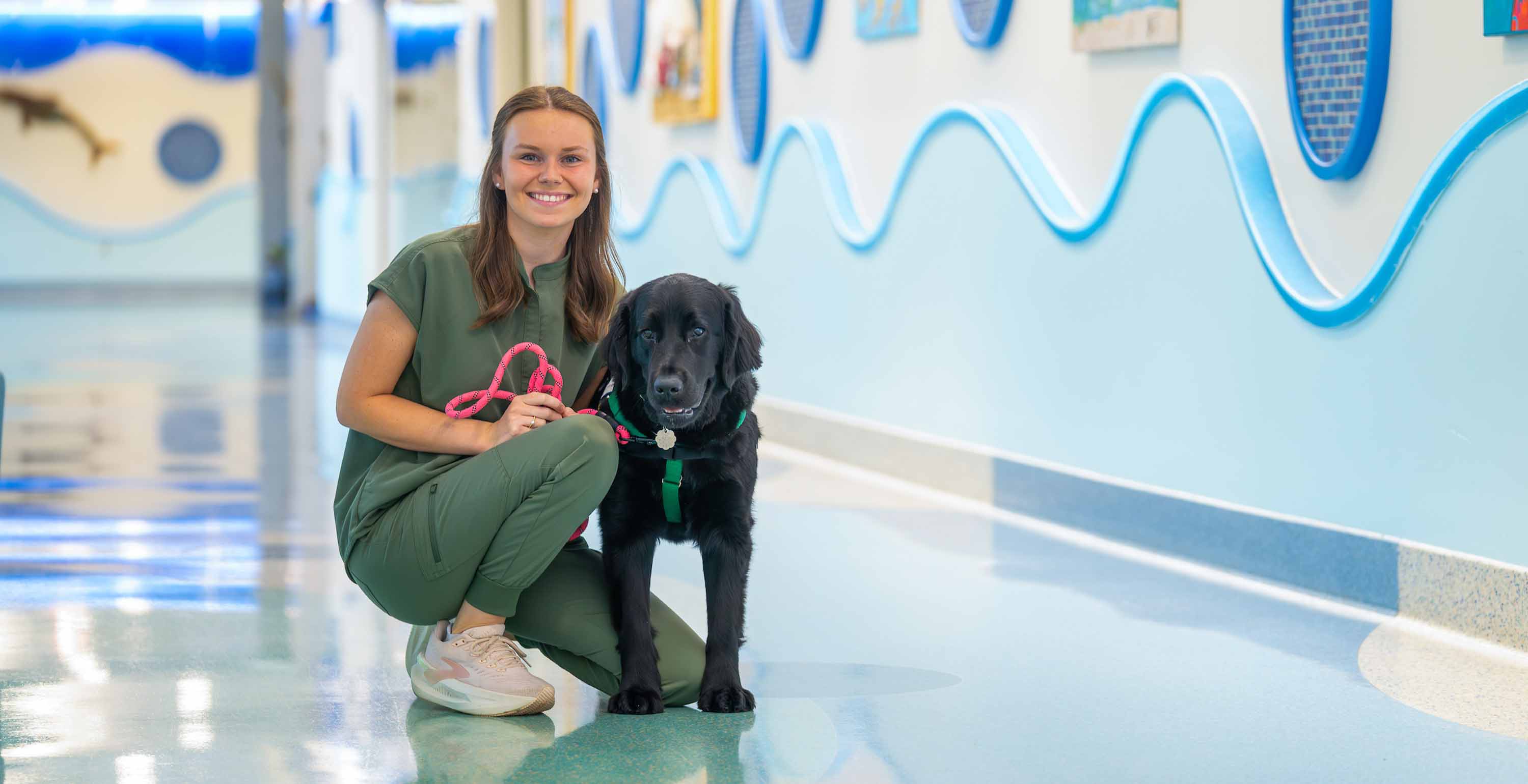 As the primary handler for USA Health Children&rsquo;s & Women&rsquo;s Hospital&rsquo;s first full-time facility dog, Rainier, South graduate Emma Bryson combines recreational therapy with the healing power of a remarkable partner. Photo is of Emma and Rainier at the hospital. 
