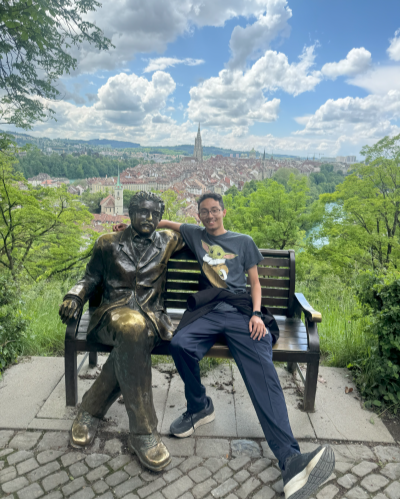 Man sitting next to statue of Albert Einstein