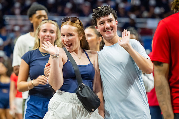 Two students waving at convocation