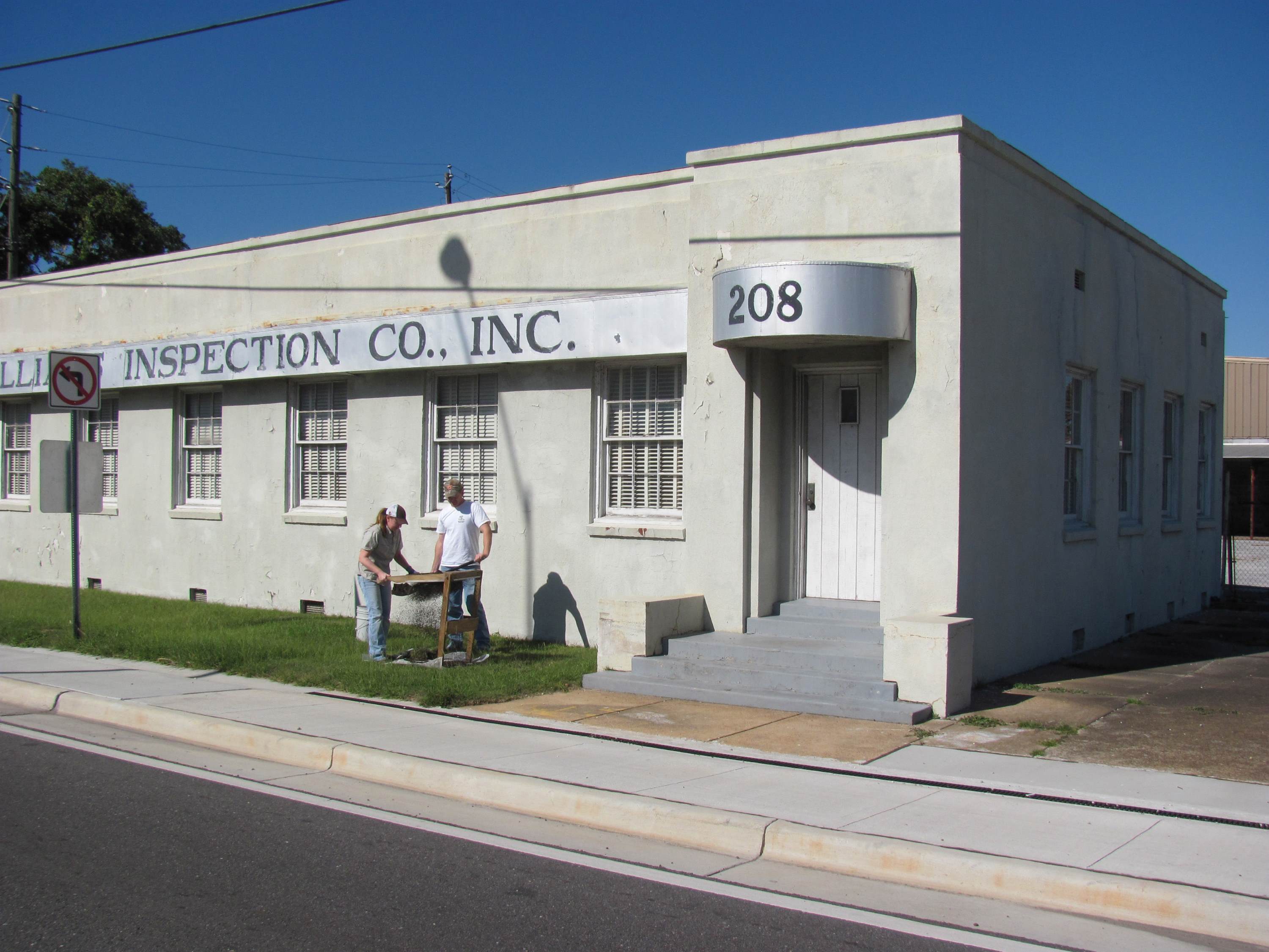 Two archaeologists excavating in front of a white building