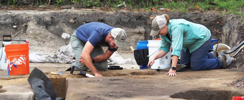Emily Warner, right, with the USA Center for Archaeological Studies, and Thomas Grace, with Wiregrass Archaeological Consulting, bisect a feature in the soil at a site that is along the route for a proposed Mobile Bay bridge. 