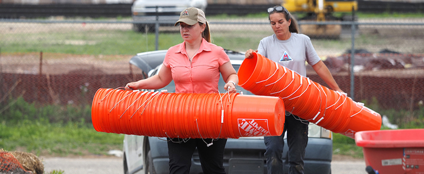 Two people carrying buckets on an archaeological site.